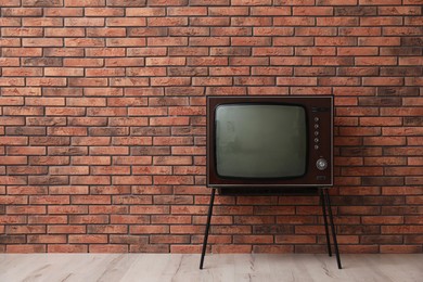 Photo of Retro TV on stand near red brick wall, space for text. Used stuff