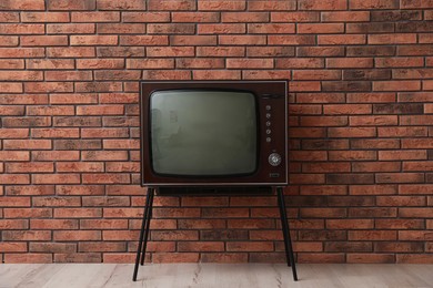 Photo of Retro TV on stand near red brick wall. Used stuff