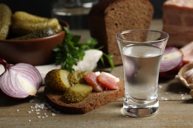 Photo of Cold Russian vodka with snacks on wooden table, closeup