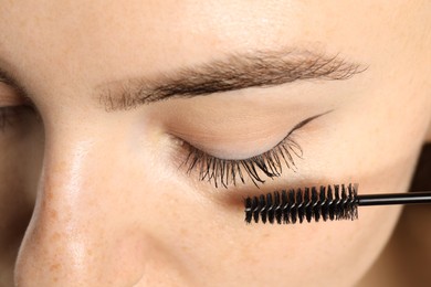 Photo of Woman applying mascara onto her eyelashes, closeup