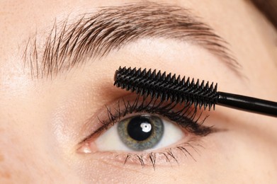 Photo of Woman applying mascara onto her eyelashes, closeup