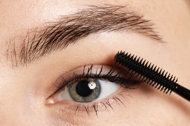Photo of Woman applying mascara onto her eyelashes, closeup