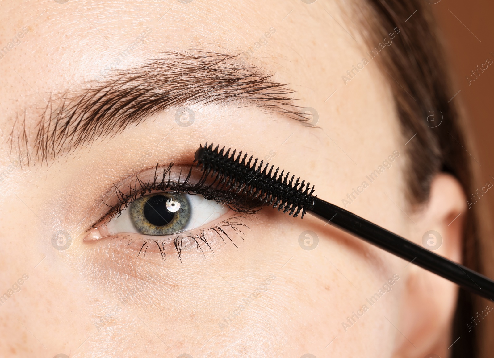 Photo of Woman applying mascara onto her eyelashes, closeup