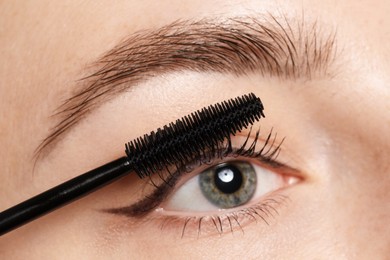 Photo of Woman applying mascara onto her eyelashes, closeup