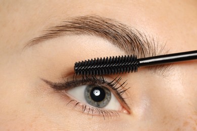Photo of Woman applying mascara onto her eyelashes, closeup
