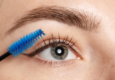 Photo of Woman applying mascara onto her eyelashes, closeup