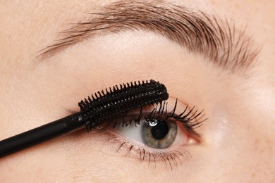 Photo of Woman applying mascara onto her eyelashes, closeup
