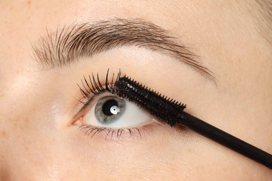 Photo of Woman applying mascara onto her eyelashes, closeup