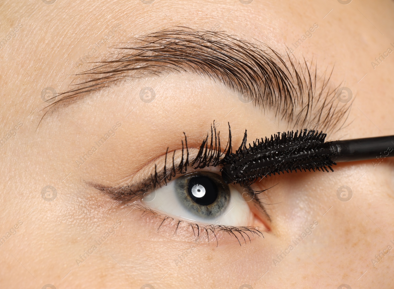 Photo of Woman applying mascara onto her eyelashes, closeup