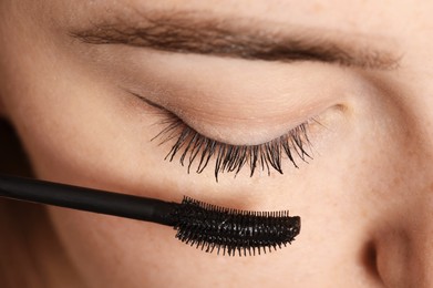 Photo of Woman applying mascara onto her eyelashes, closeup