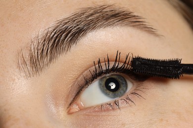 Photo of Woman applying mascara onto her eyelashes, closeup