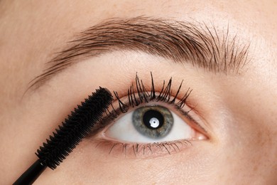 Photo of Woman applying mascara onto her eyelashes, closeup
