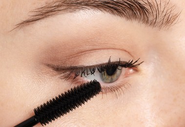 Photo of Woman applying mascara onto her eyelashes, closeup