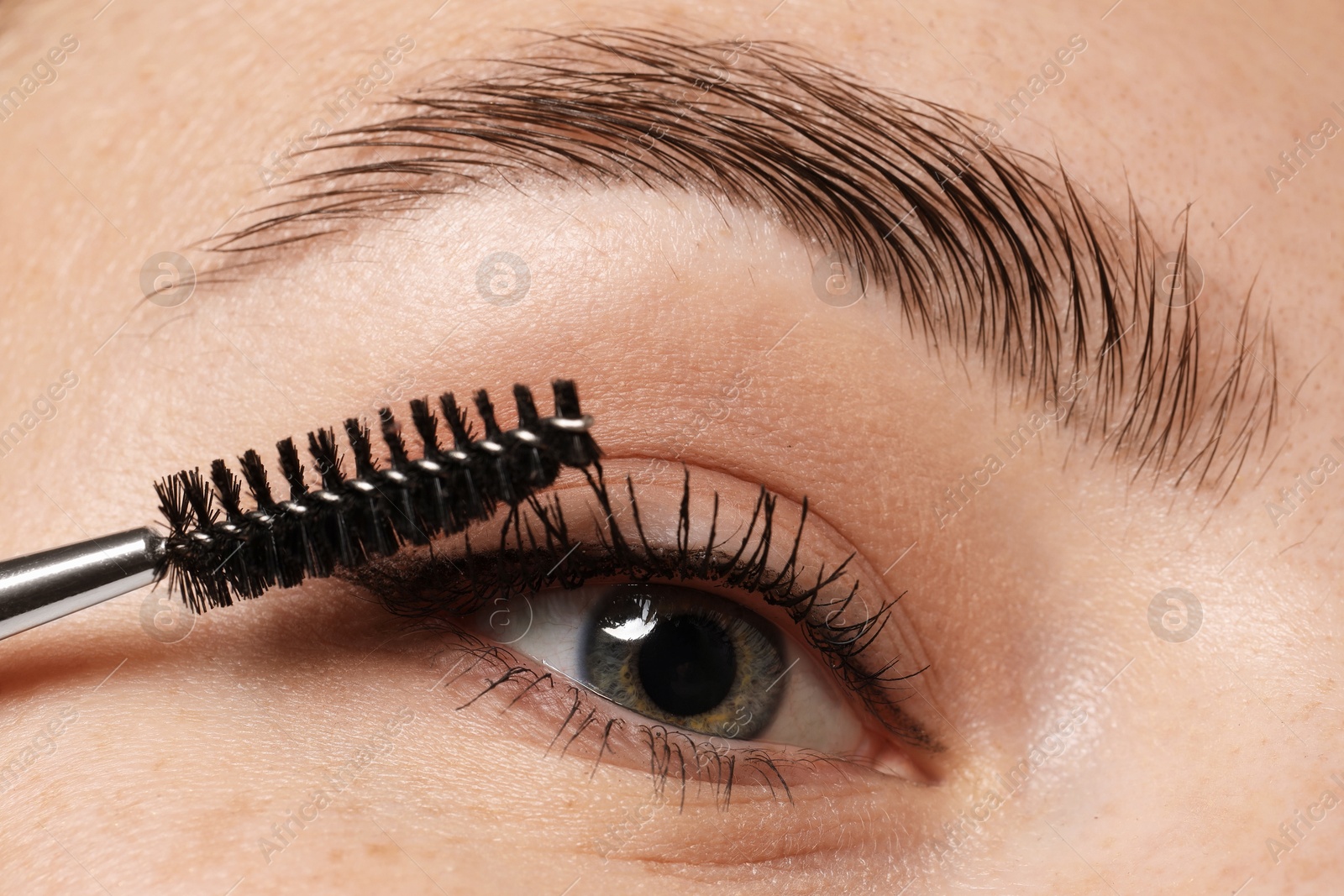 Photo of Woman applying mascara onto her eyelashes, closeup