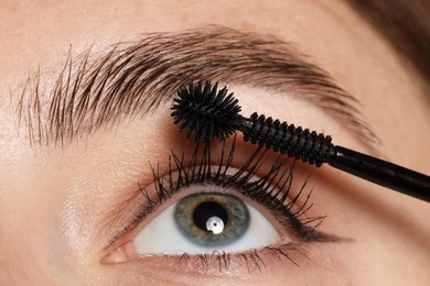 Photo of Woman applying mascara onto her eyelashes, closeup