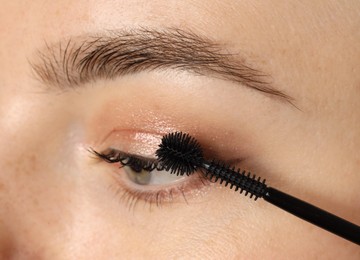Photo of Woman applying mascara onto her eyelashes, closeup