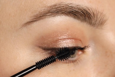 Photo of Woman applying mascara onto her eyelashes, closeup