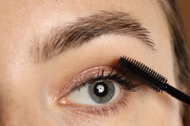 Photo of Woman applying mascara onto her eyelashes, closeup