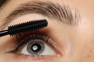 Photo of Woman applying mascara onto her eyelashes, closeup