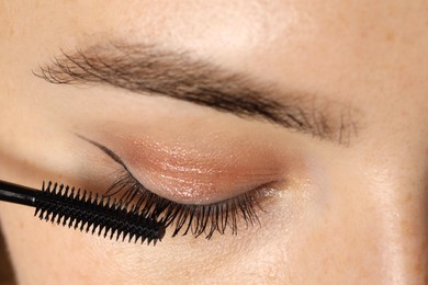 Photo of Woman applying mascara onto her eyelashes, closeup