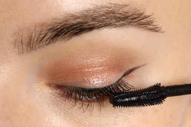 Photo of Woman applying mascara onto her eyelashes, closeup