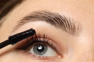 Photo of Woman applying mascara onto her eyelashes, closeup