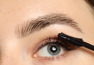 Photo of Woman applying mascara onto her eyelashes, closeup