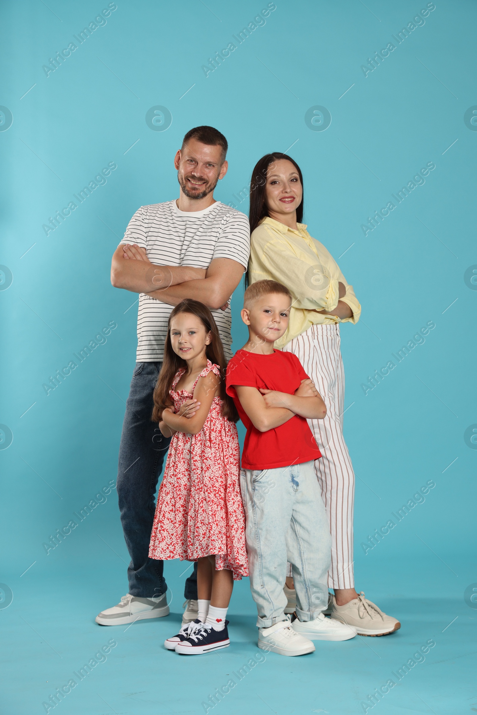 Lovely family posing together on light blue background Photo of Lovely family posing together on light blue background