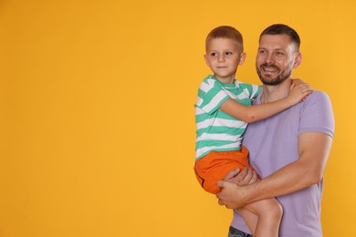 Photo of Happy father and son on yellow background. Space for text