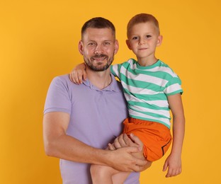 Photo of Happy father and son on yellow background