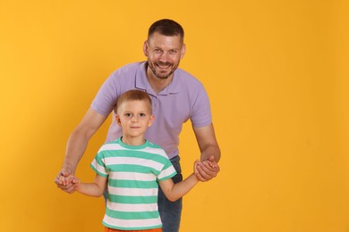 Photo of Happy father and son on yellow background. Space for text