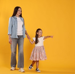 Photo of Daughter showing her mother something on yellow background