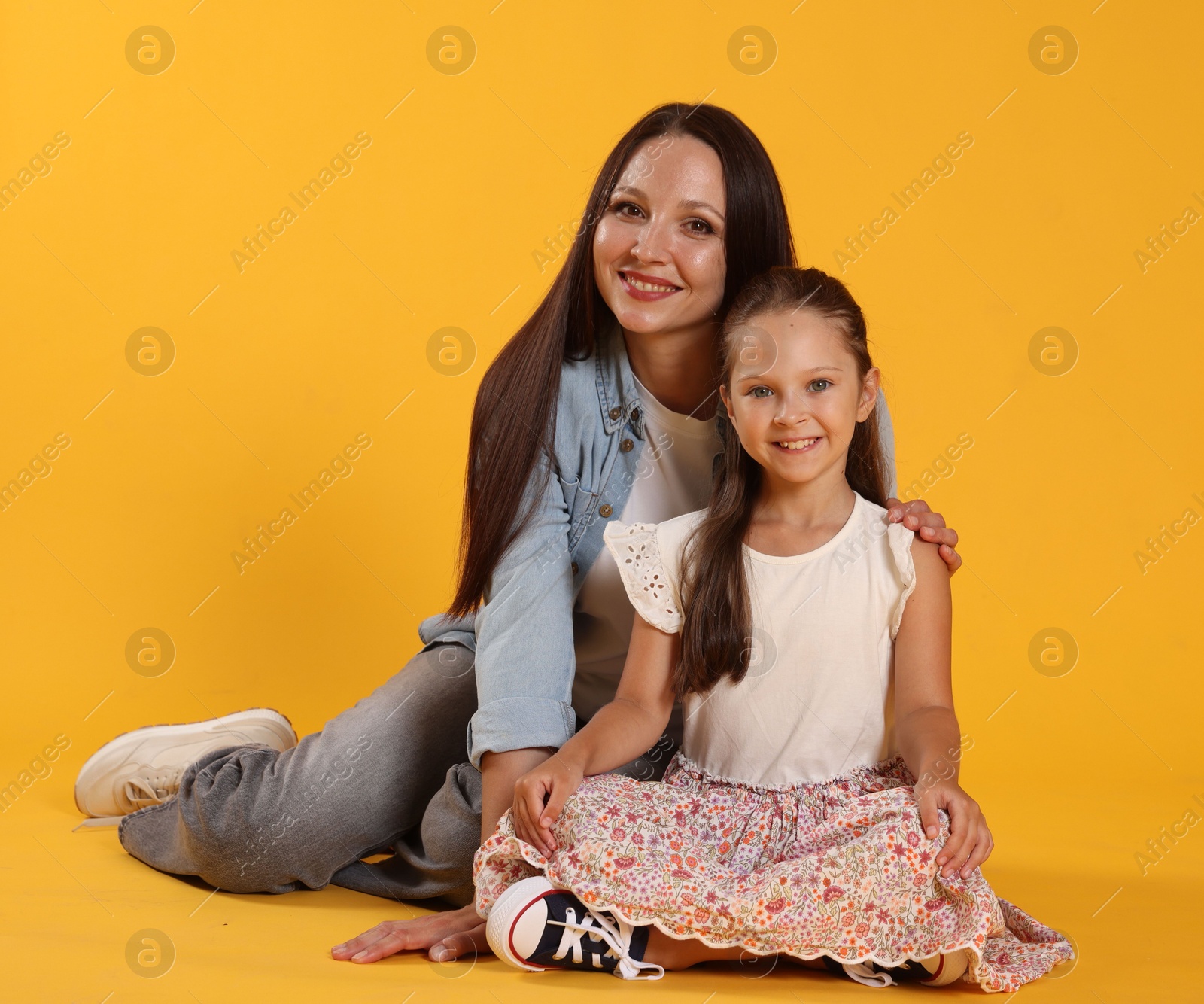 Photo of Lovely mother and daughter on yellow background