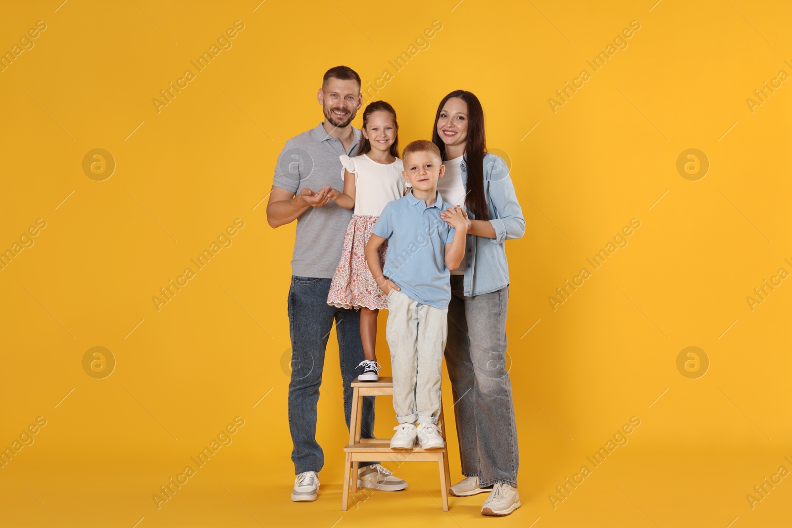 Photo of Lovely family posing together on yellow background