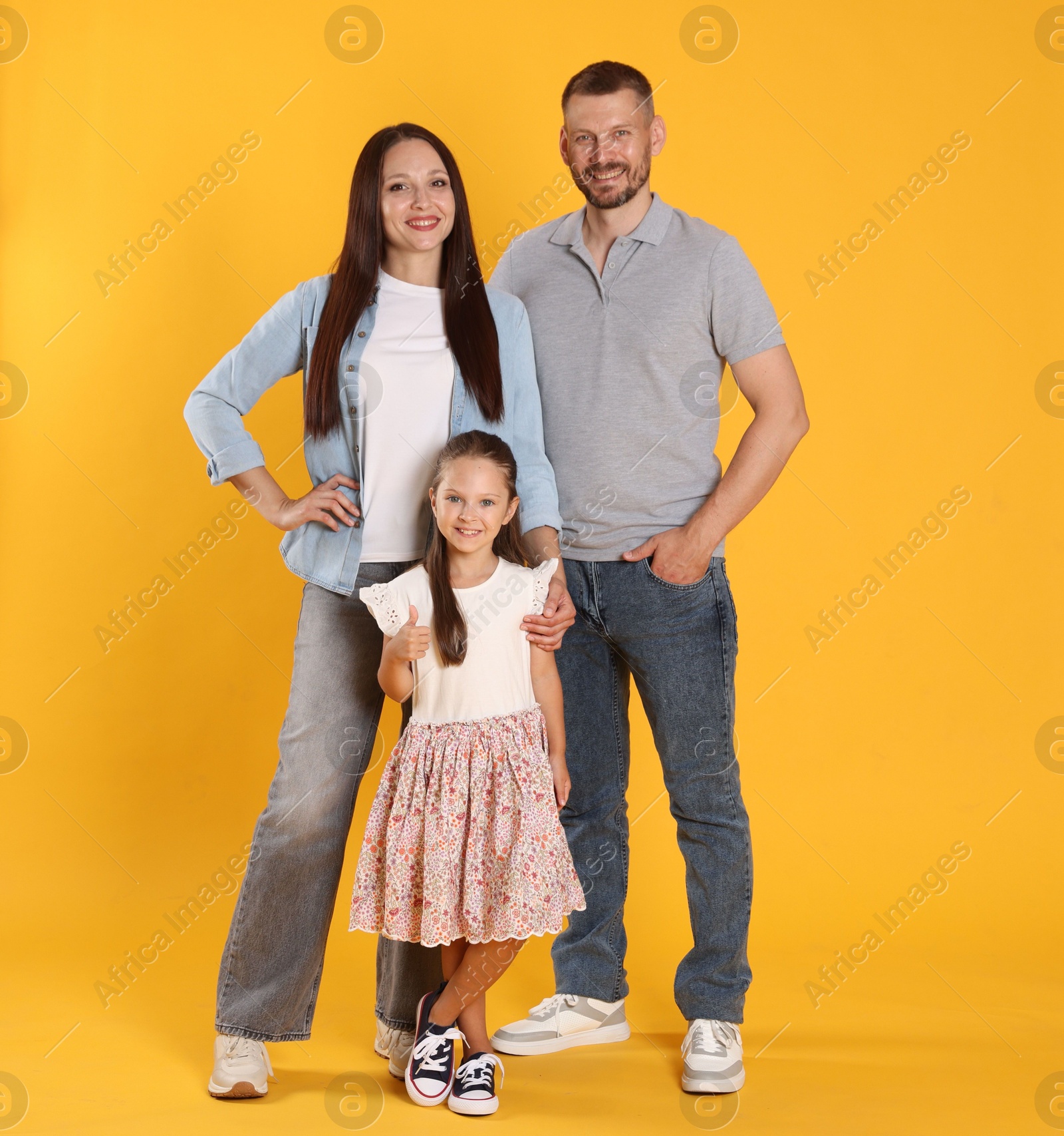 Lovely family posing together on yellow background Photo of Lovely family posing together on yellow background