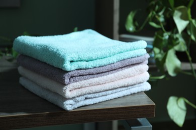 Photo of Stack of fresh terry towels on wooden table indoors, closeup