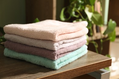 Photo of Stack of fresh terry towels on wooden table indoors, closeup