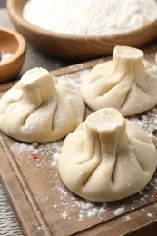 Photo of Uncooked khinkalis (dumplings) on wooden table, closeup