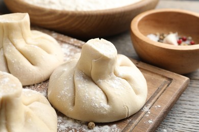 Photo of Uncooked khinkalis (dumplings) on wooden table, closeup