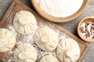 Photo of Uncooked khinkalis (dumplings) and spices on wooden table, flat lay