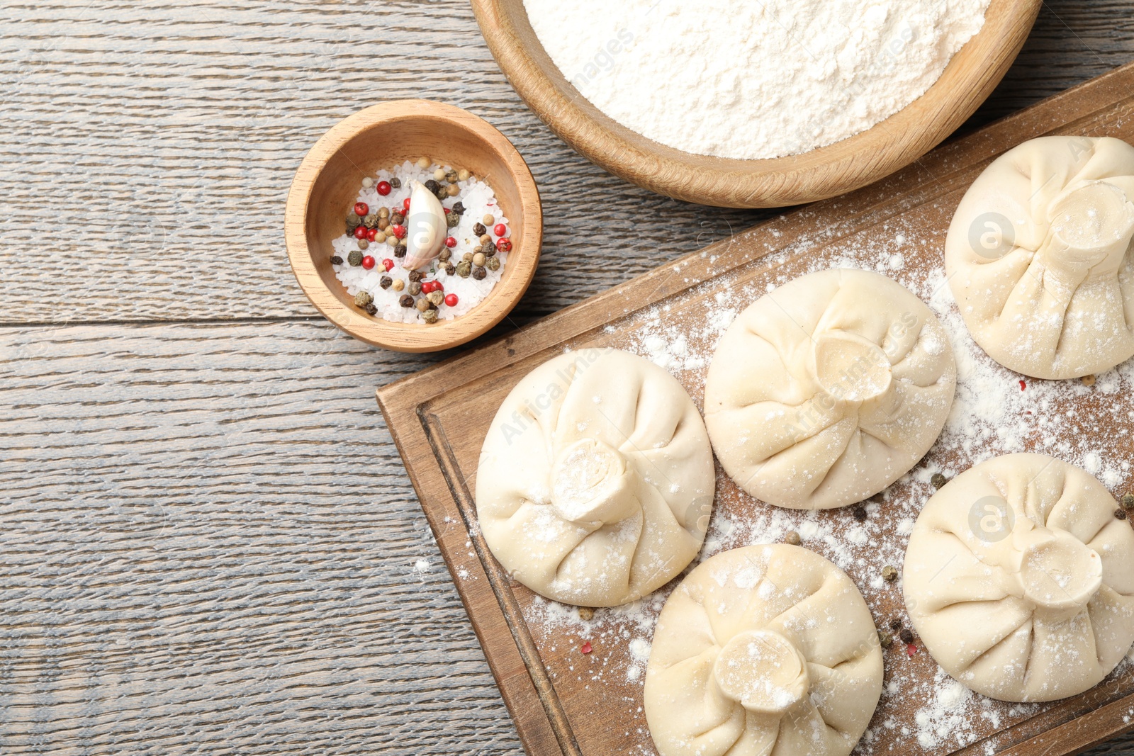 Photo of Uncooked khinkalis (dumplings) and spices on wooden table, flat lay. Space for text