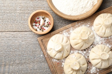 Photo of Uncooked khinkalis (dumplings) and spices on wooden table, flat lay. Space for text