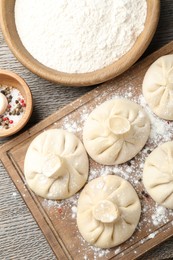 Photo of Uncooked khinkalis (dumplings) and spices on wooden table, flat lay