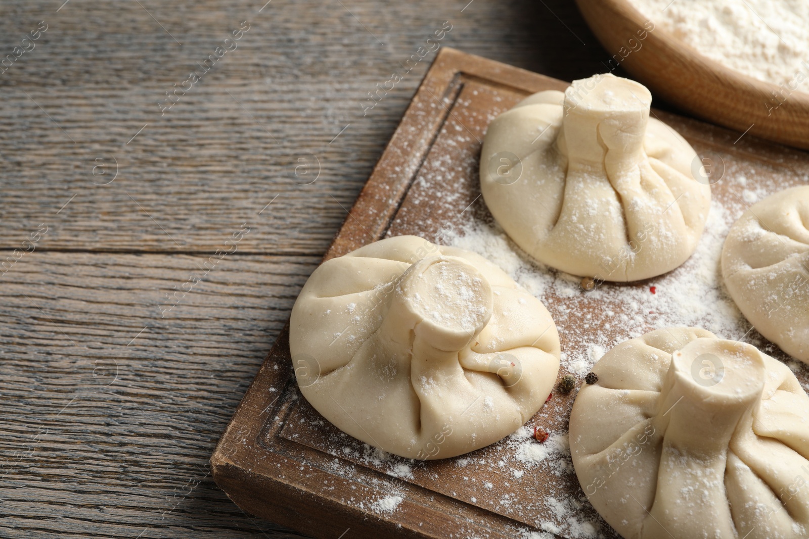 Uncooked khinkalis (dumplings) on wooden table, closeup. Space for text Photo of Uncooked khinkalis (dumplings) on wooden table, closeup. Space for text
