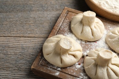 Photo of Uncooked khinkalis (dumplings) on wooden table, closeup. Space for text