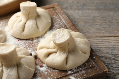 Photo of Uncooked khinkalis (dumplings) on wooden table, closeup