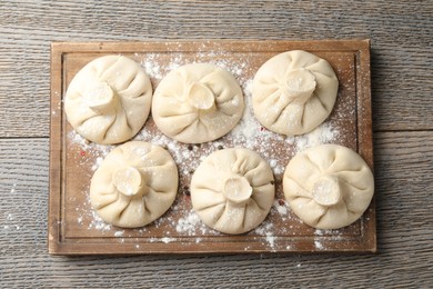 Photo of Uncooked khinkalis (dumplings) on wooden table, top view