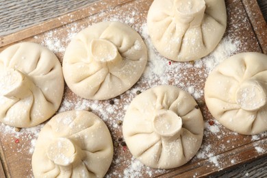 Photo of Uncooked khinkalis (dumplings) on wooden table, top view