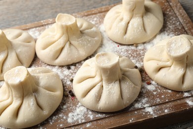Photo of Uncooked khinkalis (dumplings) on wooden table, closeup