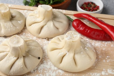 Photo of Uncooked khinkalis (dumplings) and chili pepper on table, closeup